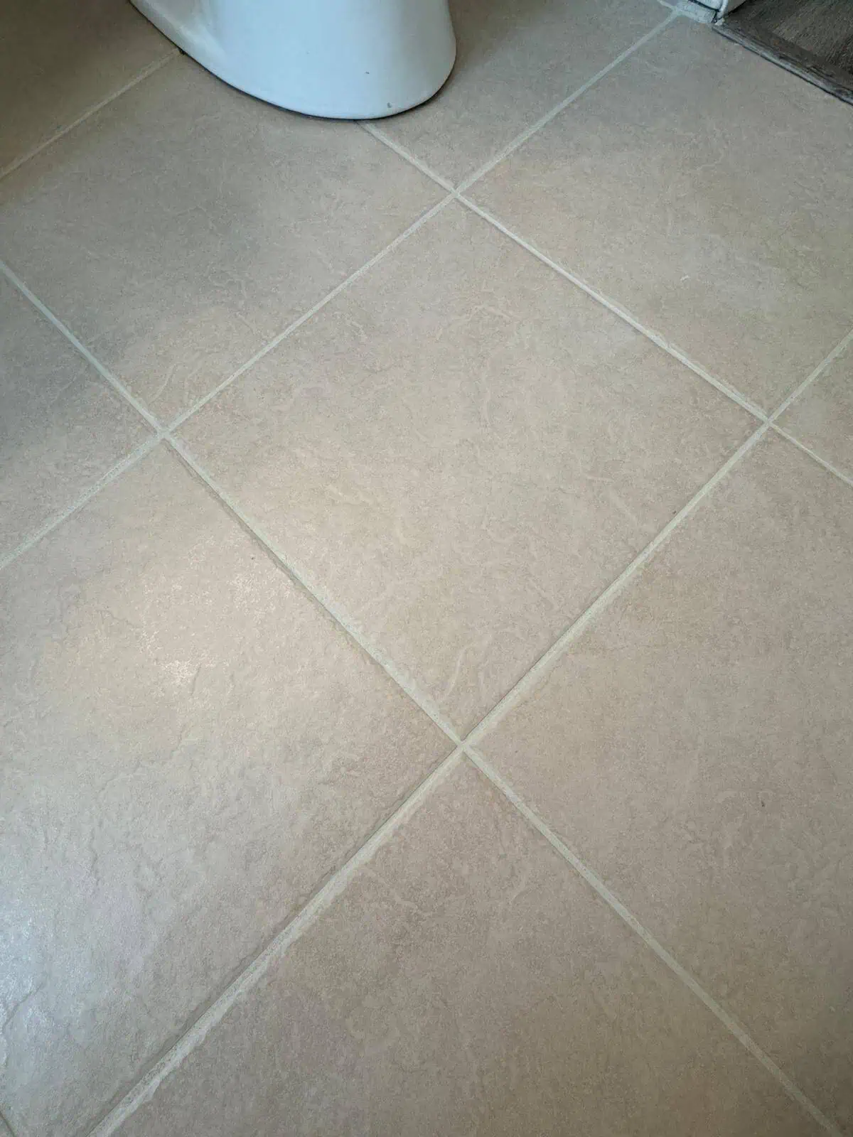 Close-up of beige tiled floor with grout lines, showcasing professional tile installation.